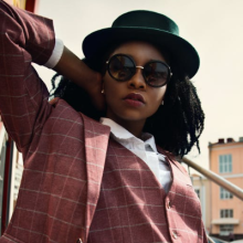 Woman in hat, sunglasses, and suite.