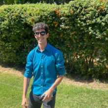 Here's me with a blue shirt, sunglasses with a ¨J + N¨ on each glass, smiling and having a good time. I also have short curly hair with a mole (lunar) in which are some grey hair.