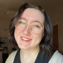 Photo of a caucasian woman with dark shoulder-length hair and glasses.