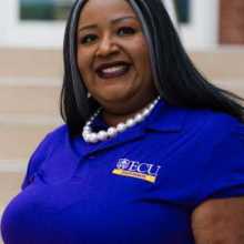 lady smiling wearing a purple shirt and a pearl necklace