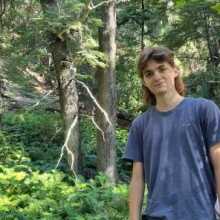 The picture shows me surrounded by a green forest