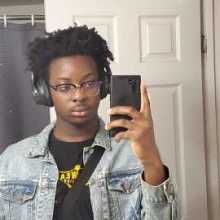 Picture of this user taking a mirror selfie. He is wearing a black shirt with a denim jacket over it