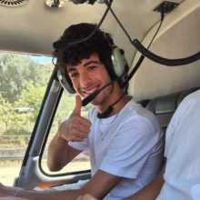 Young man smiling while sitting in a helicopter wearing pilot headphones