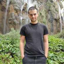 A man standing in front of the waterfall