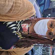 Femme person with yellow glasses, white face mask and black floral shirt