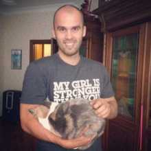 A man embraces a cat in his arms, displaying a warm and loving connection.