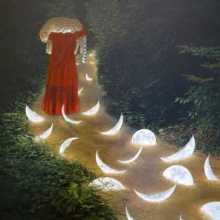 Woman walking in forest of illuminated moons