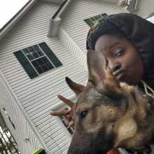 A woman sitting in front of her house with her dog.
