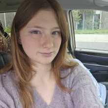 Picture of a woman with long ginger hair, a purple sweater and purple eyeshadow