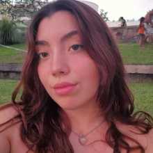 A woman with long brown hair wearing a necklace, smiling softly at the camera.