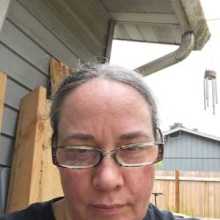 Alison G sitting outside, glasses on