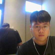 A person smiling at a café with sunlight in the background.