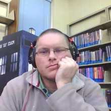 Man in gray hoodie wearing headphones in the library