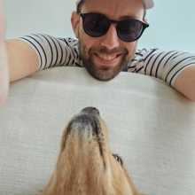 Man smiling with a dog looking up at him