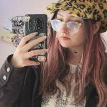 picture of me, brown hair with pink highlights and glasses, with a brown jacket and leopard print hat