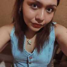 Mujer joven tomándose una selfie desde arriba. Lleva el cabello lacio y suelto con raya al medio, maquillaje en tonos marrones y labial oscuro.