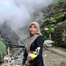 A person is standing in a mountain crater area, with natural surroundings visible in the background. 