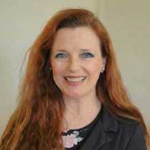 Portrait of a 55-year old professional woman with long red hair.