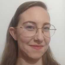 A blond woman in light-colored glasses. She is smiling slightly at the camera.