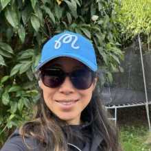 A woman where wearing sunglasses and blue cap in a garden.