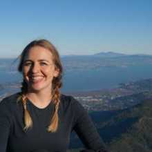 girl smiling for photo with blue sky and mountains in the background. Located at Mt. Tam in the Bay Area.