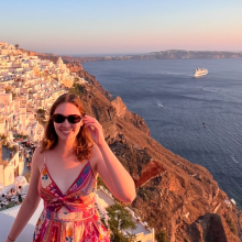 smiling woman by a coastal town on a cliffside by the sea