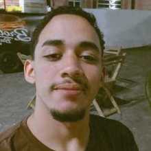A young Latino man is wearing a brown shirt.