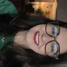 A smiling woman, long dark hair, wearing glasses 