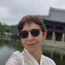 Femme portant un vêtement traditionnel coréen devant un bâtiment historique.