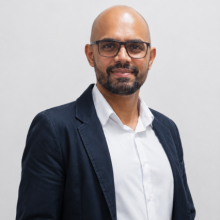 Professional portrait of a Brazilian Mechatrhonic engineering student wearing glasses and a blue blazer.