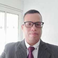 Foto de perfil de un hombre colombiano sonriendo frente a un fondo claro