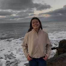 A photo of a girl with the sea behind her.