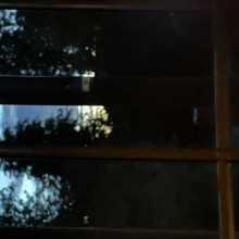 A picture of the sky behind a window it’s blue cloudy and dark.