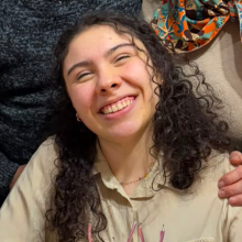 Mujer sonriendo con el pelo largo y rizado, vistiendo una camisa clara.¿Necesitas ayuda con algún otro campo o instrucción de este formulario?    
