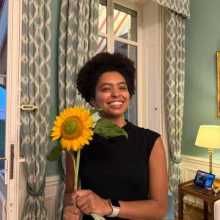 A woman in a black shirt holding a large yellow sunflower