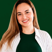 Portrait of Mary Miller, a smiling UX/UI designer with long hair, wearing a white jacket against a dark green background